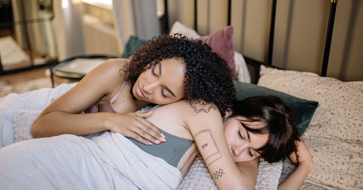 Two women embracing in a cozy bedroom, expressing love and affection.