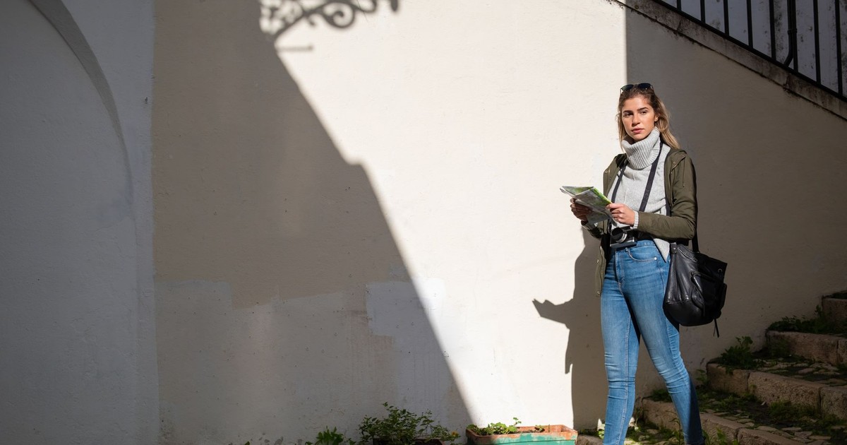 Woman with a map exploring a city street, embracing adventure and travel.