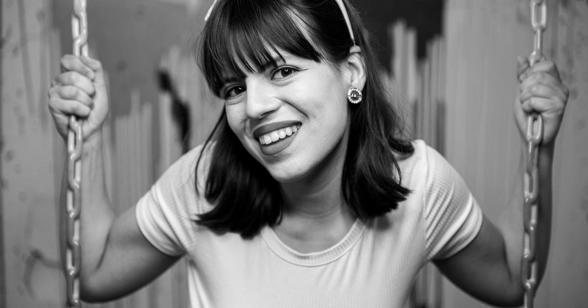 Playful portrait of a smiling woman on a swing, captured in monochrome.