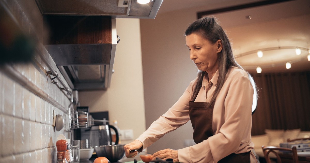 Elderly woman prepares food in a warm, cozy kitchen environment. Home cooking vibe.