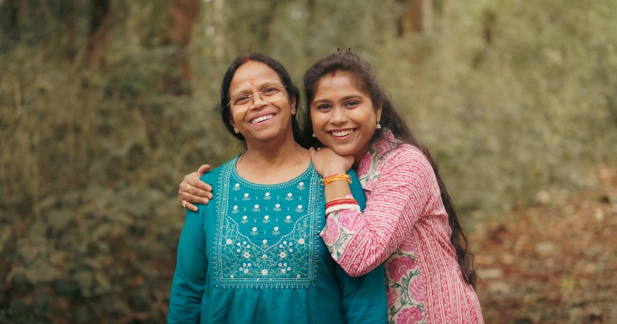 A joyful mother and daughter celebrating togetherness in a forest backdrop.