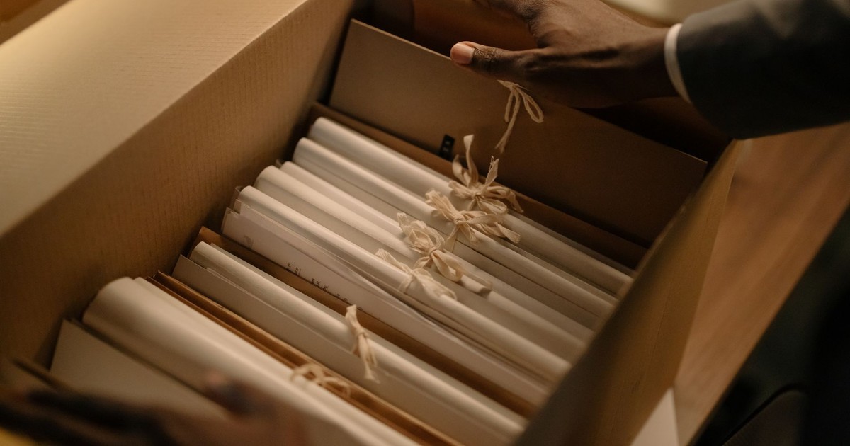 Hands organizing files in a box, symbolizing investigation and research.