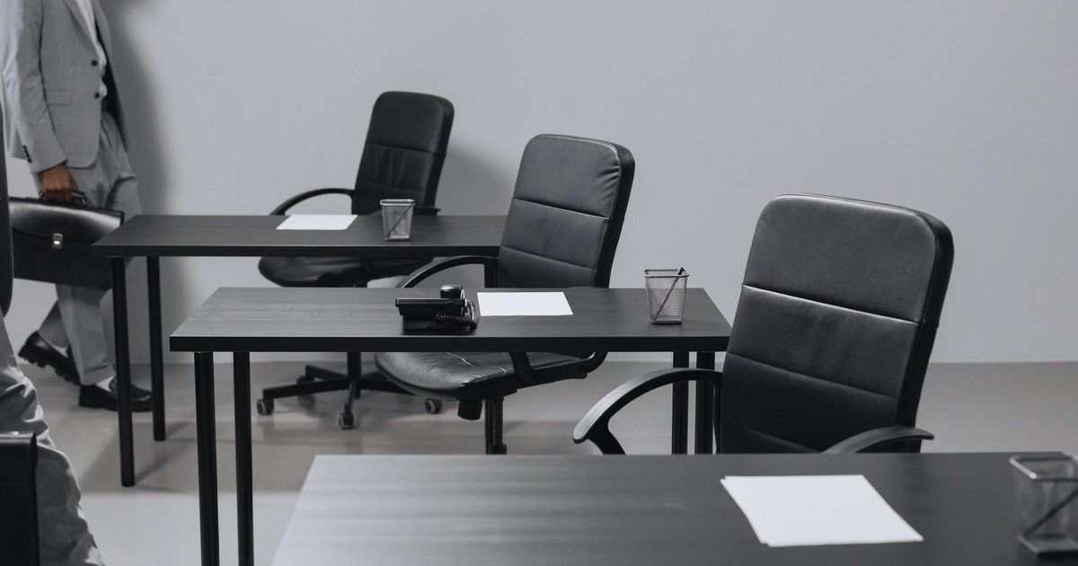 Contemporary office space with black leather chairs and desks, showcasing a minimalist design.