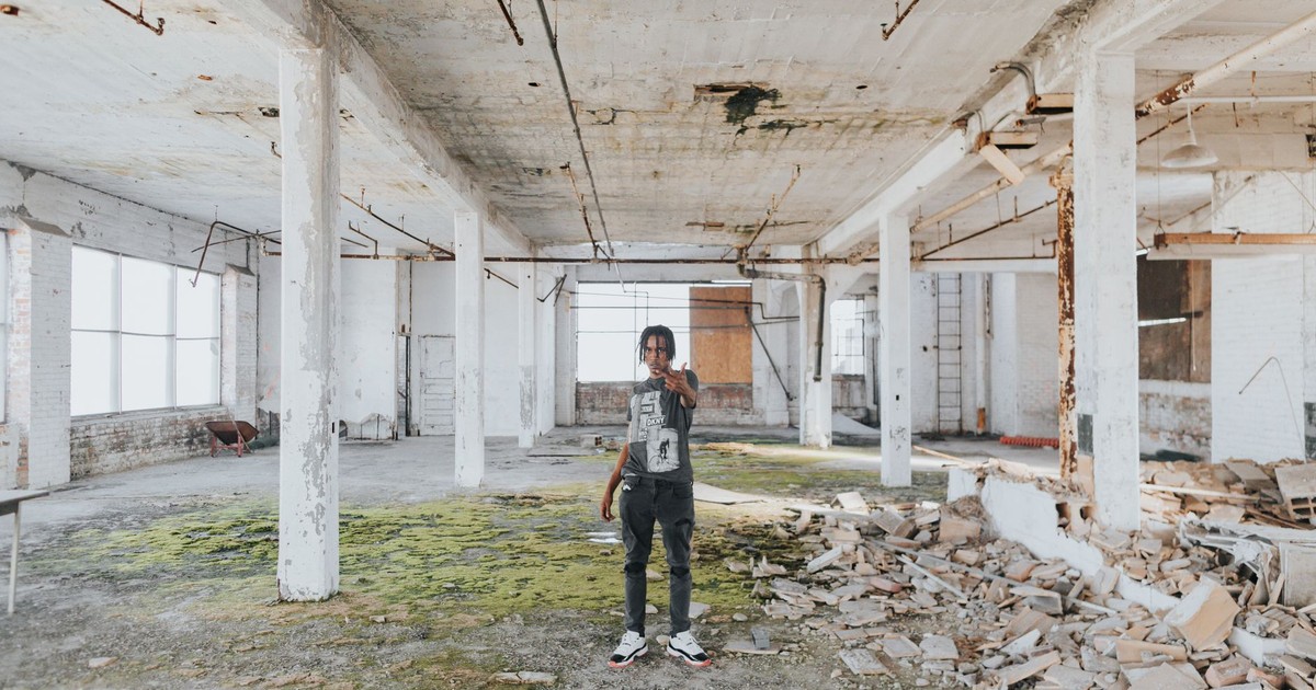 Person posing in an abandoned warehouse in Detroit, showcasing urban decay and exploration.