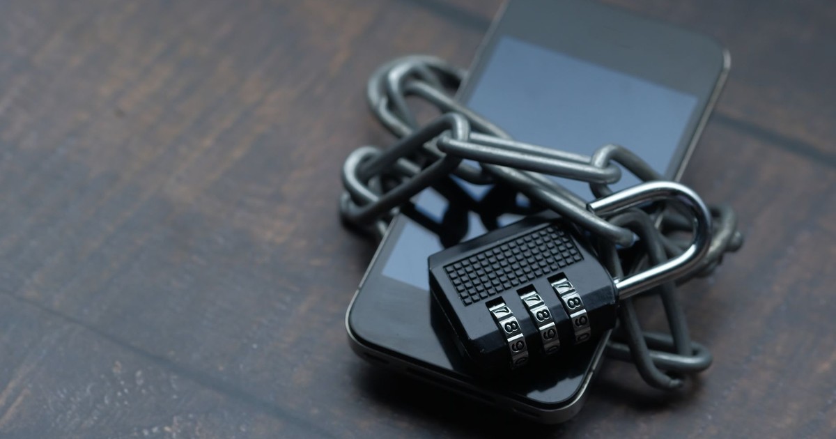 Close-up of a smartphone wrapped in a chain with a padlock, symbolizing strong security.