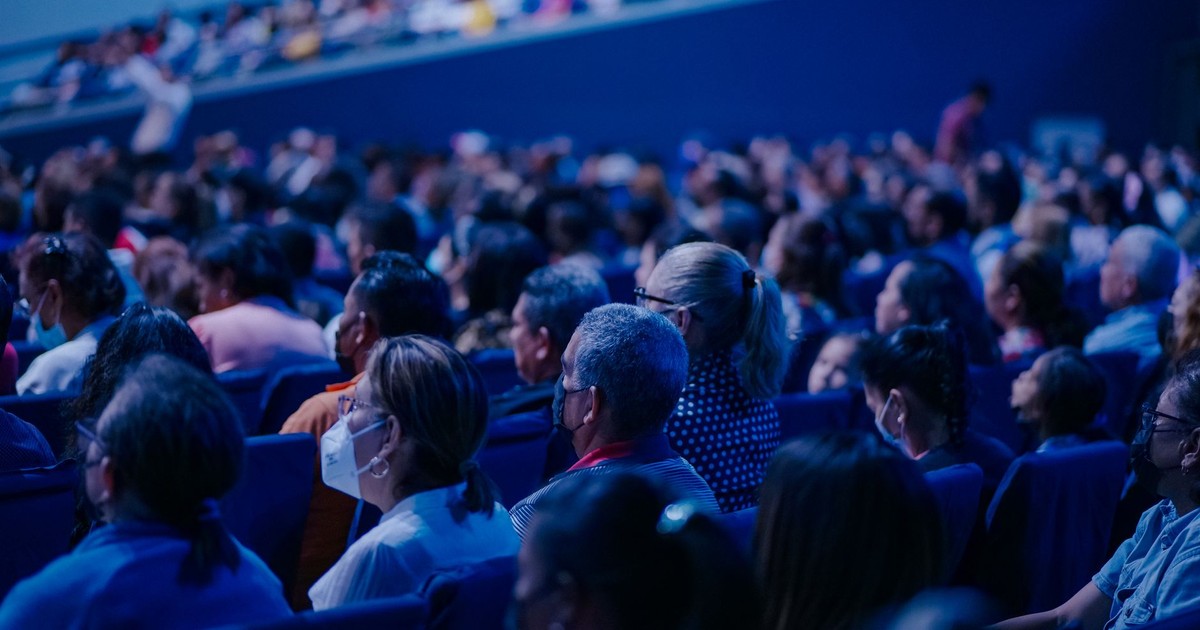 Diverse audience sitting in rows, attending an indoor conference or event.