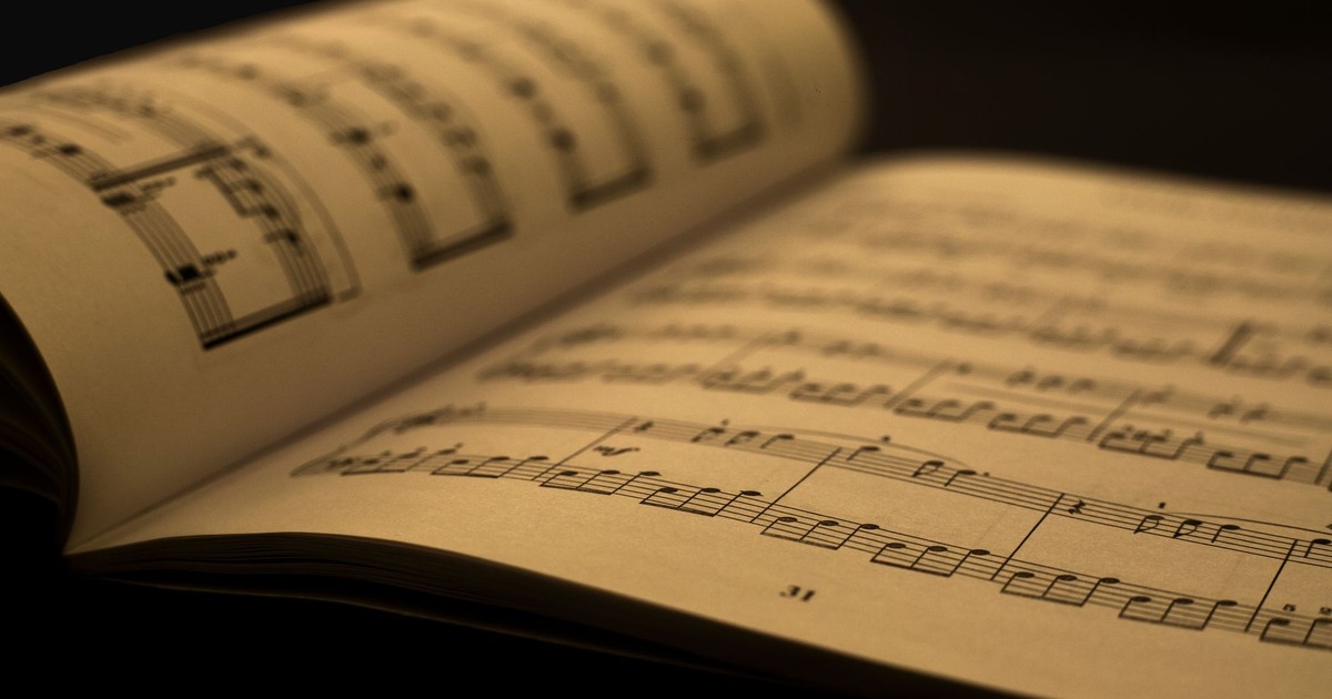 Detailed close-up of an open music sheet book, showcasing musical notes and composition in warm tones.