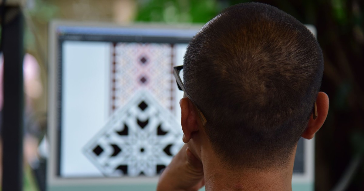 Adult focused on intricate pattern design on computer indoors.