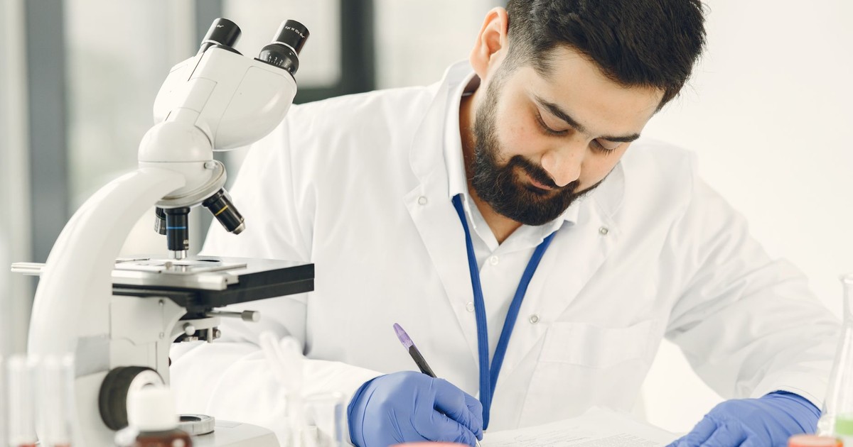 Male scientist in a laboratory, examining samples and taking notes.
