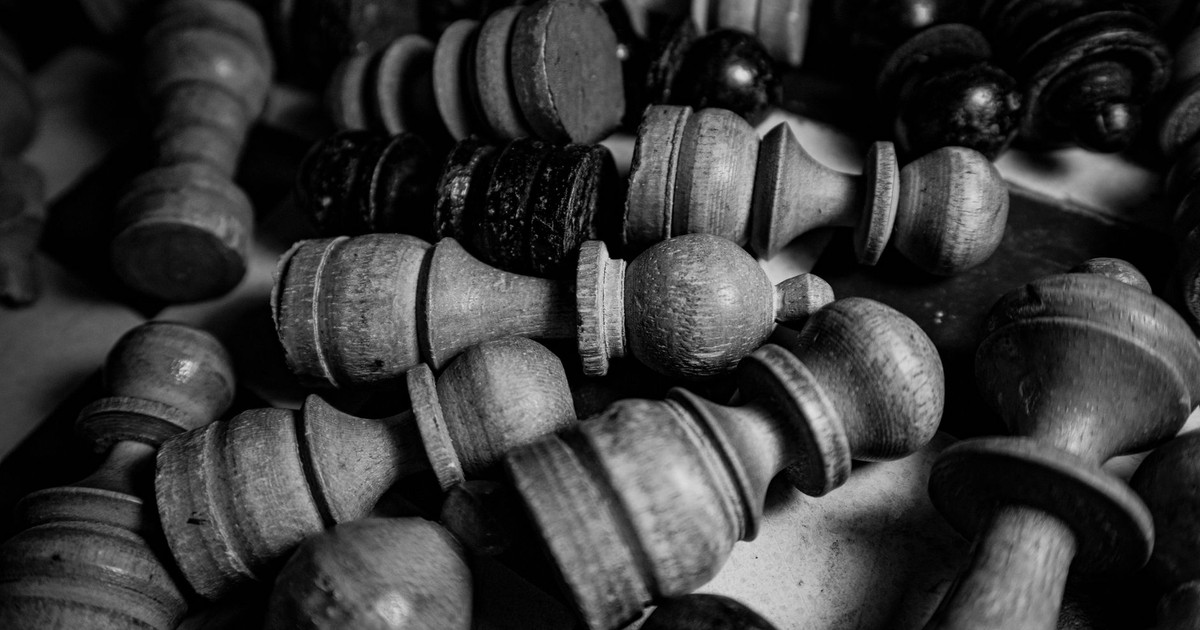 Close-up of vintage wooden chess pieces in a grayscale still life setting.