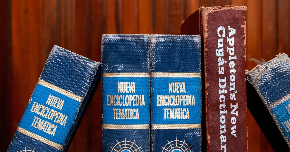 Close-up of old encyclopedias and a dictionary on a wooden shelf, showcasing vintage charm.