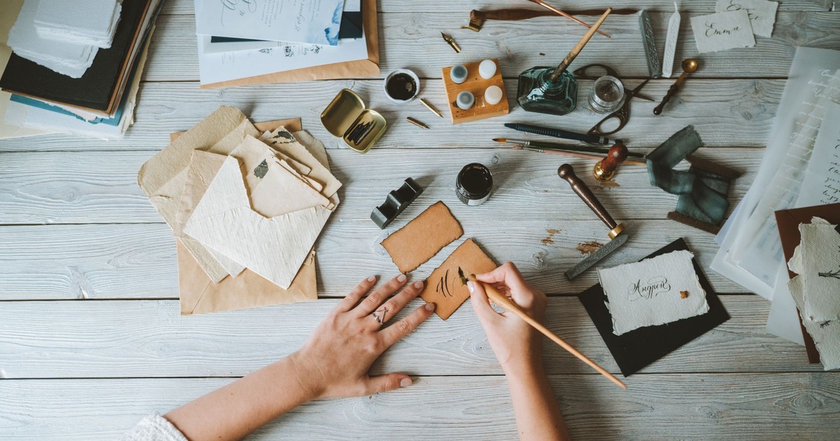 A creative flat lay of a calligraphy workstation with paper, pens, and ink.