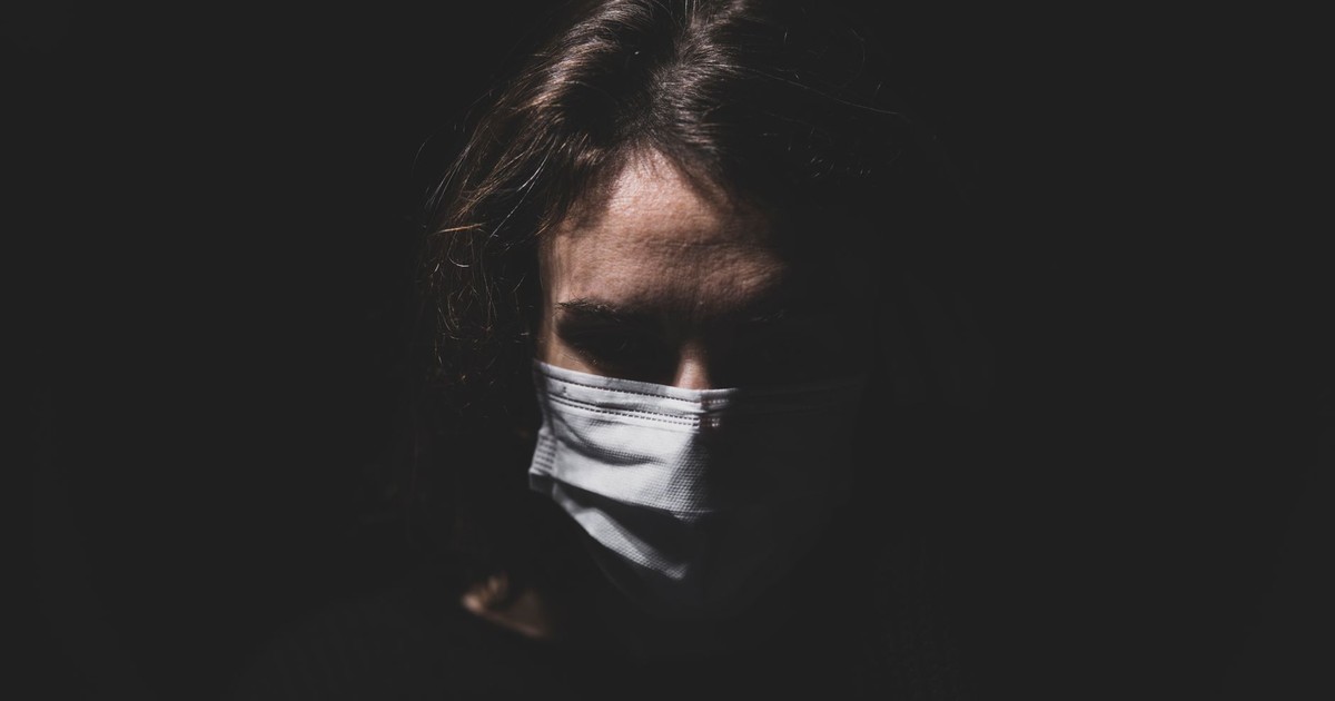 Dramatic portrait of a woman wearing a face mask, highlighting themes of health and quarantine.