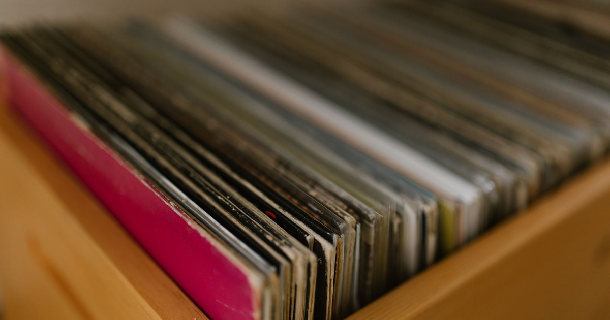 A collection of vintage vinyl records stored in a wooden shelf, showcasing a blurred background.