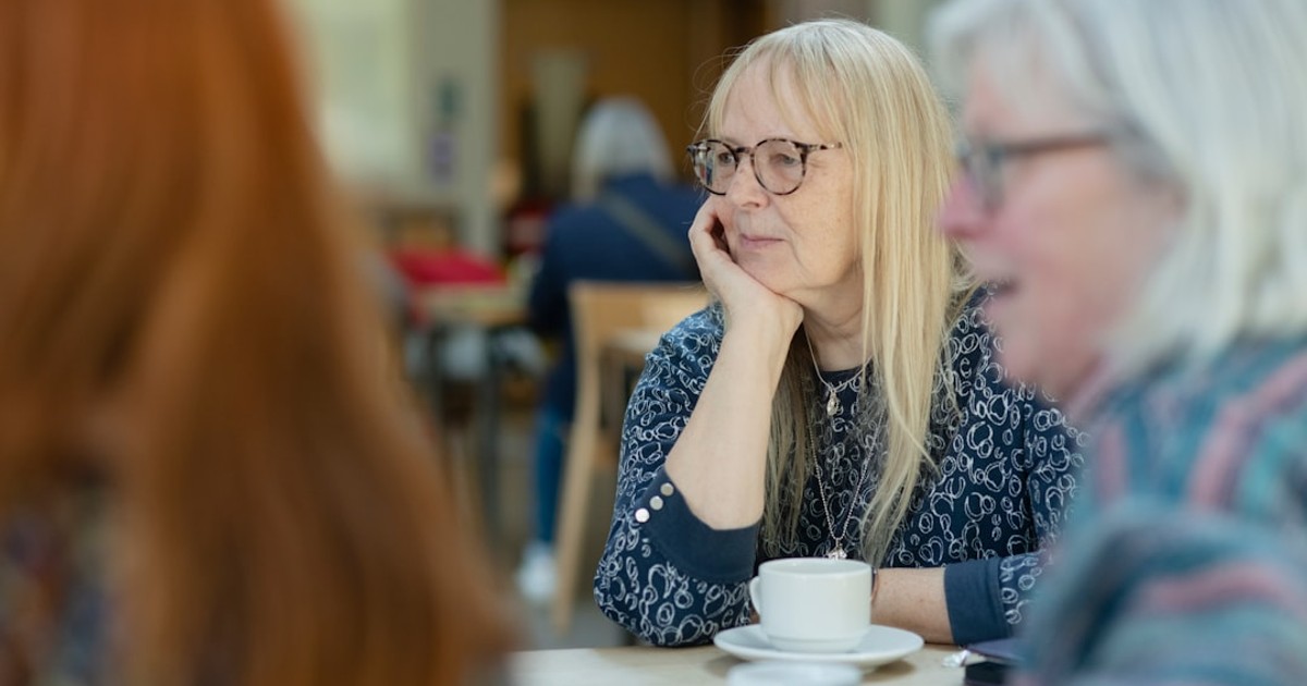 a woman sitting at a table with a cup of coffee
