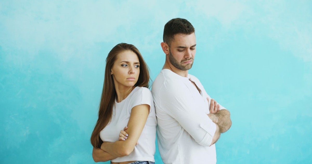 Couple standing back to back with arms crossed