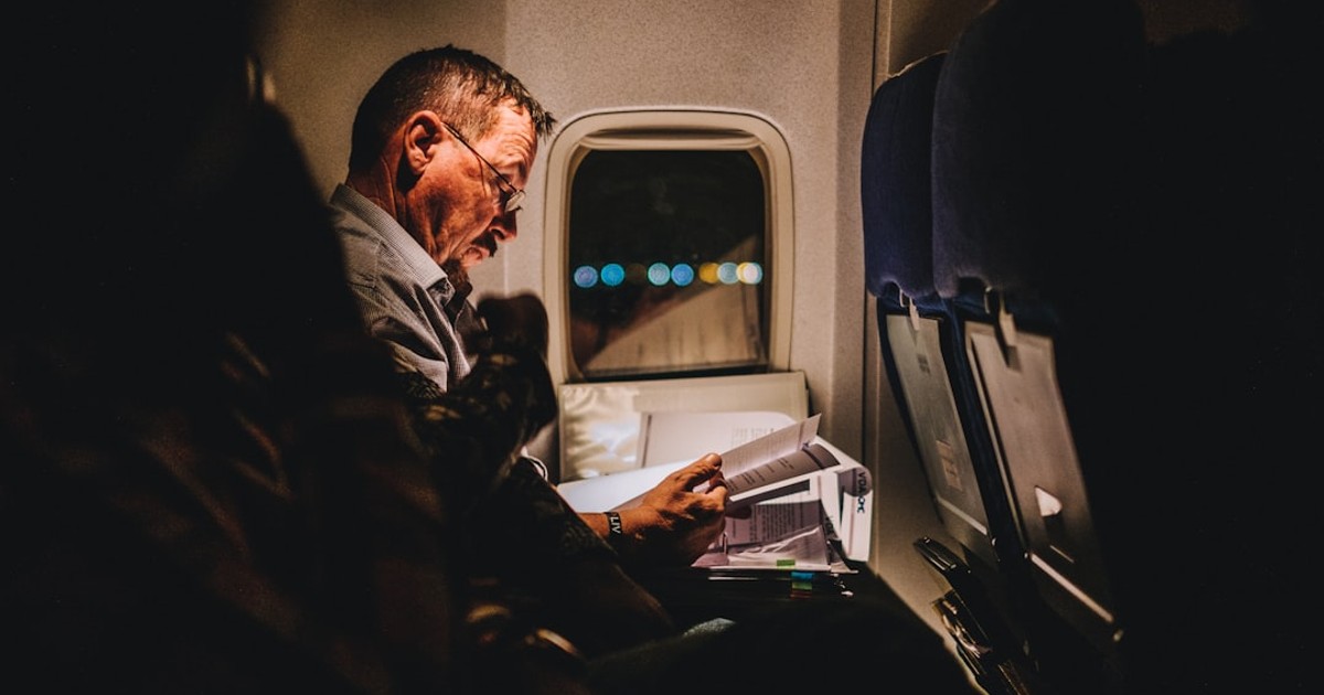 man reading book inside vehicle