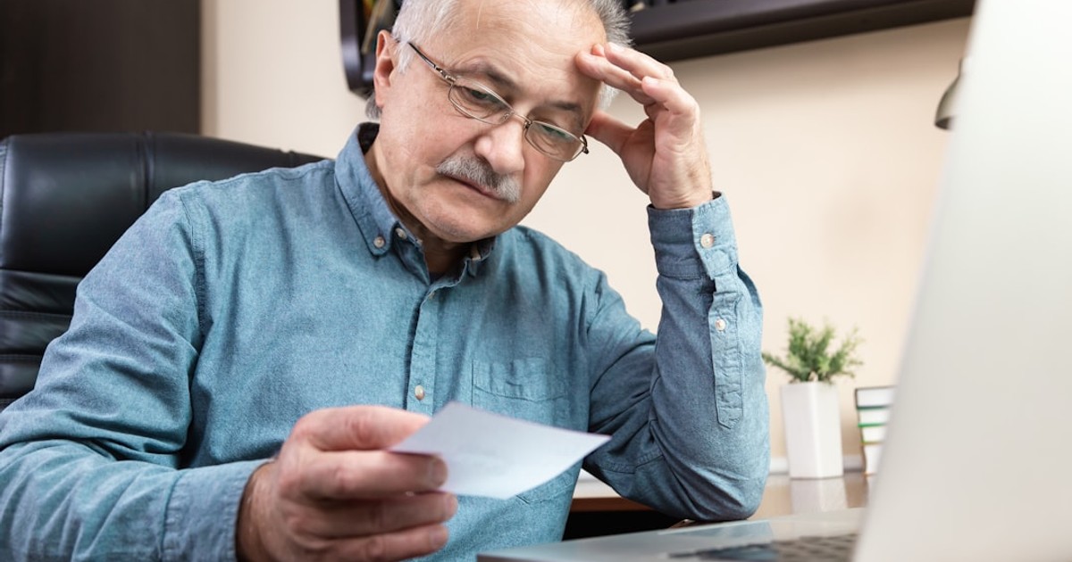 a man holding a pen and looking at a laptop