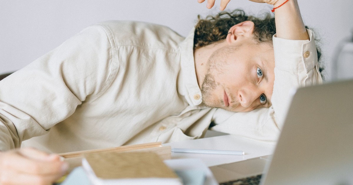 A tired Caucasian man at a desk, showing signs of exhaustion and stress, exemplifying workplace burnout.