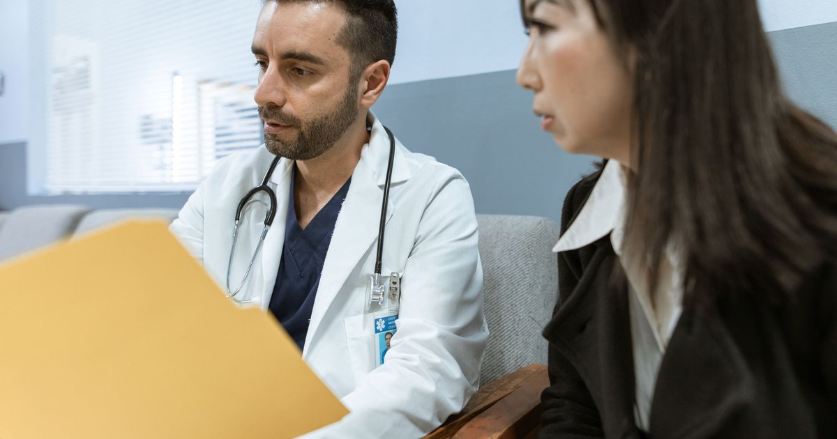Doctor discusses health records with a patient in a clinical setting.