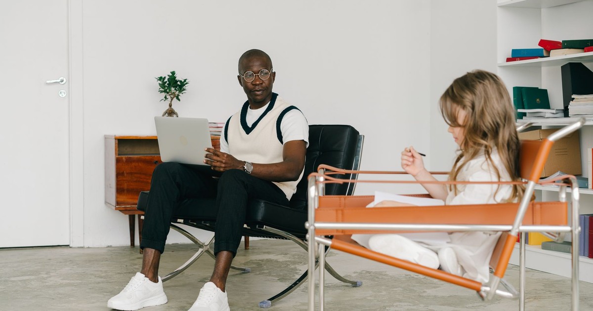 Psychologist and young girl in a therapy room, engaging in conversation and analysis.