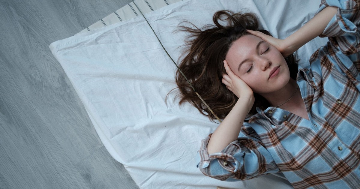Young woman relaxing indoors on a bed, embracing tranquility and calmness.