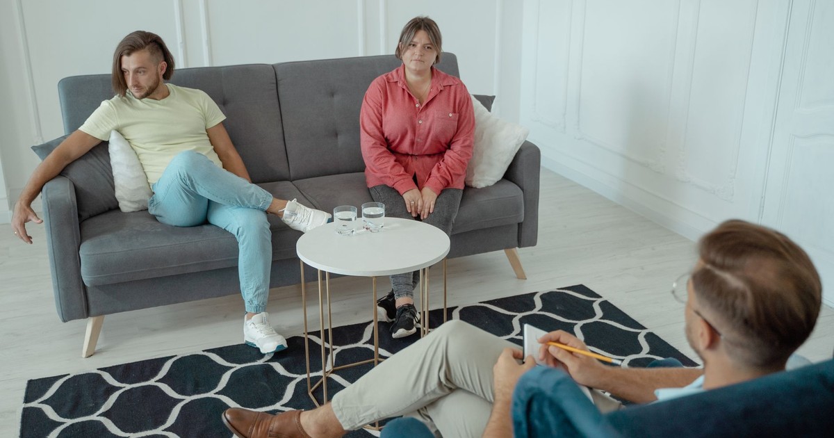 A couple attends a therapy session in a modern styled office setting, with a counselor sitting across from them.