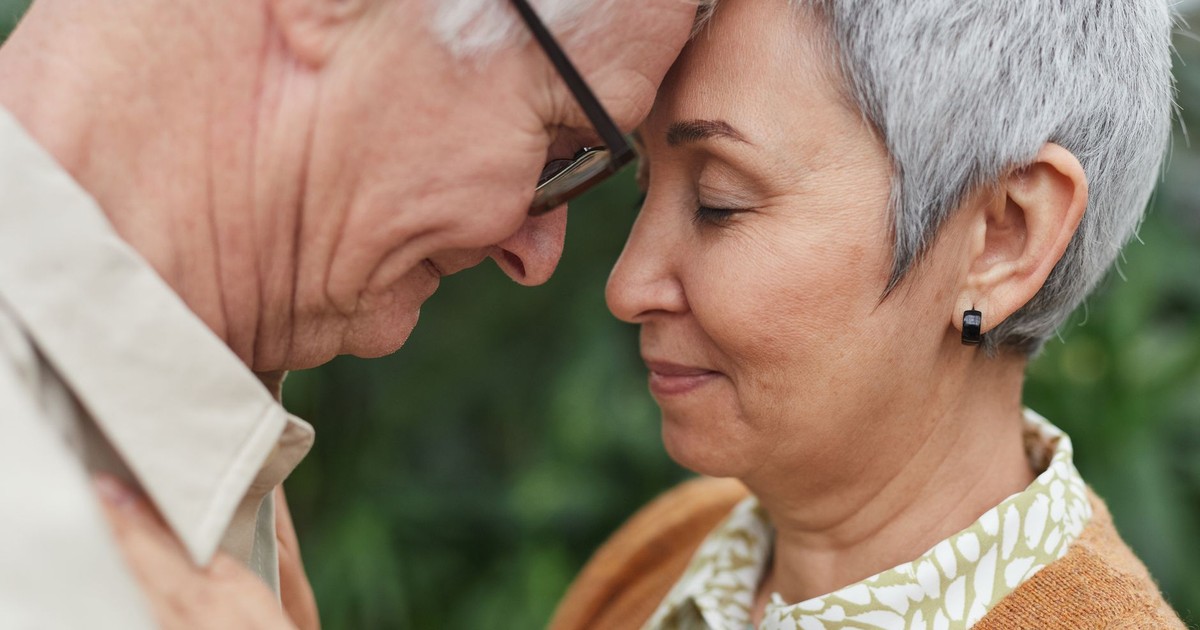 A tender moment between a senior couple, expressing love and affection outdoors.