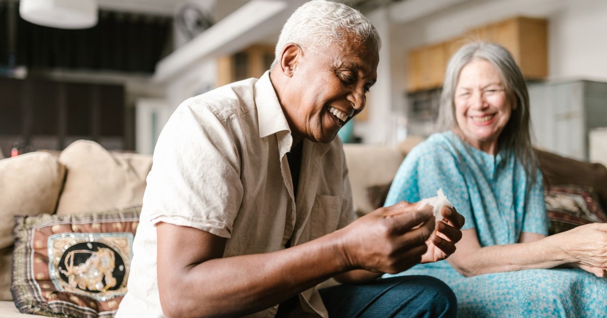 A joyful senior couple sharing a moment of laughter on the sofa in a cozy indoor setting.