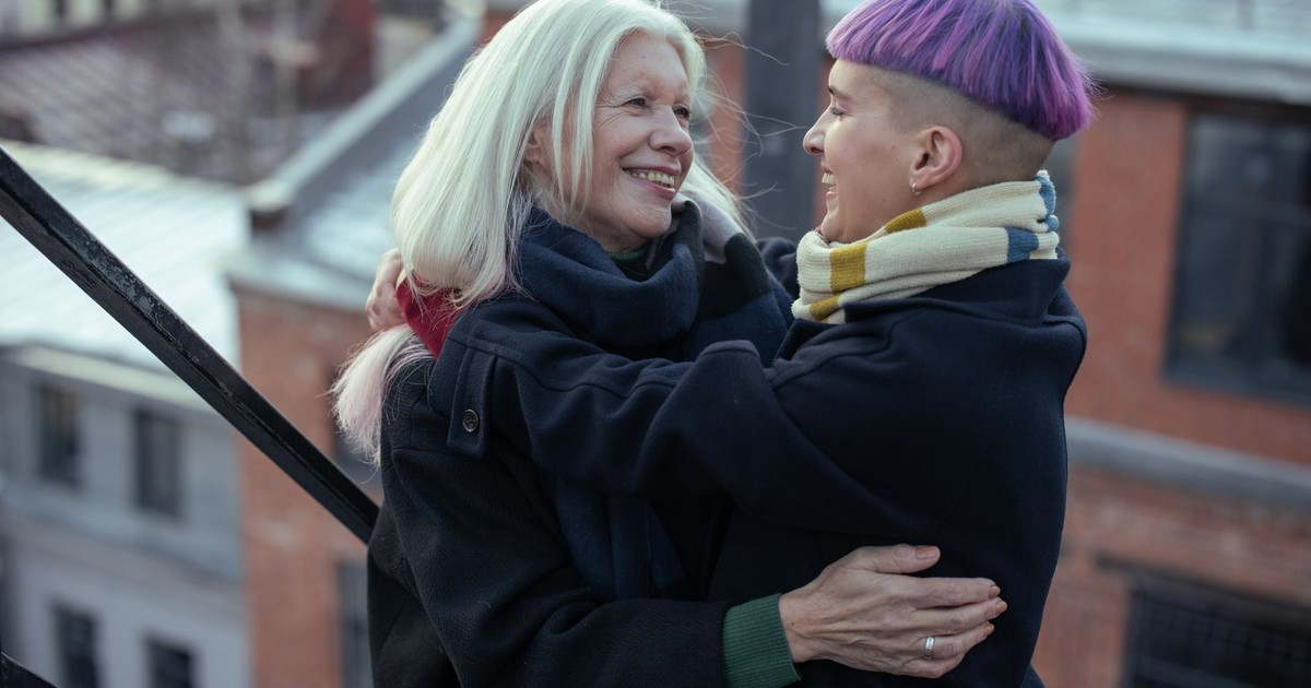 Happy moment between two women embracing on an urban terrace in winter.