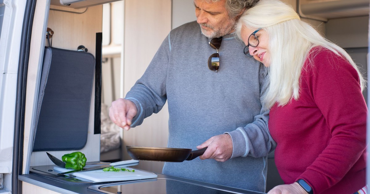 Senior couple cooking together in a motorhome kitchen during a travel trip in Portugal.