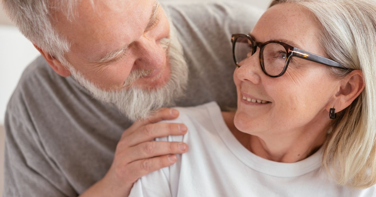 Senior couple smiling and enjoying each other's company indoors.