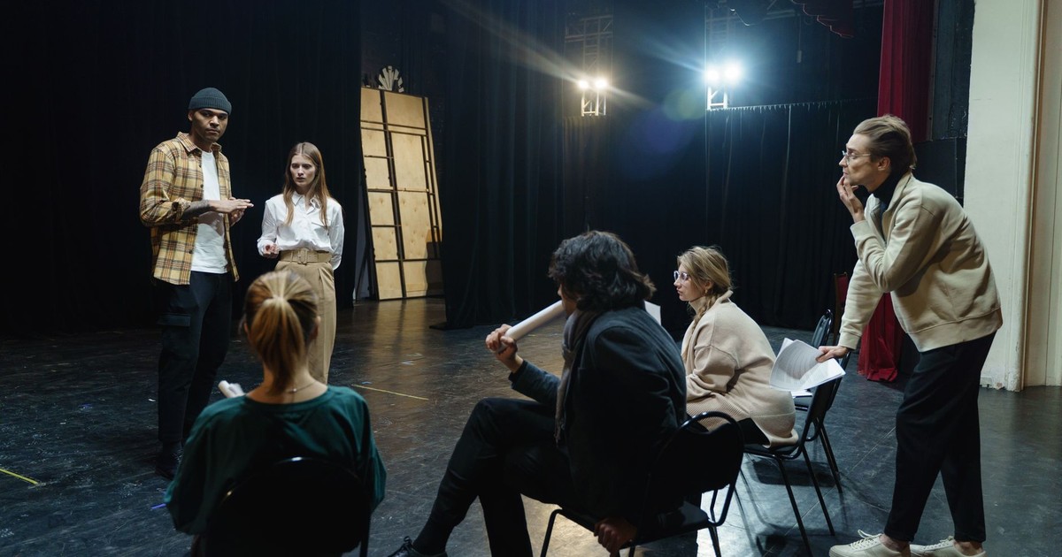 Actors rehearsing on stage with director's guidance in a theater for a live performance.