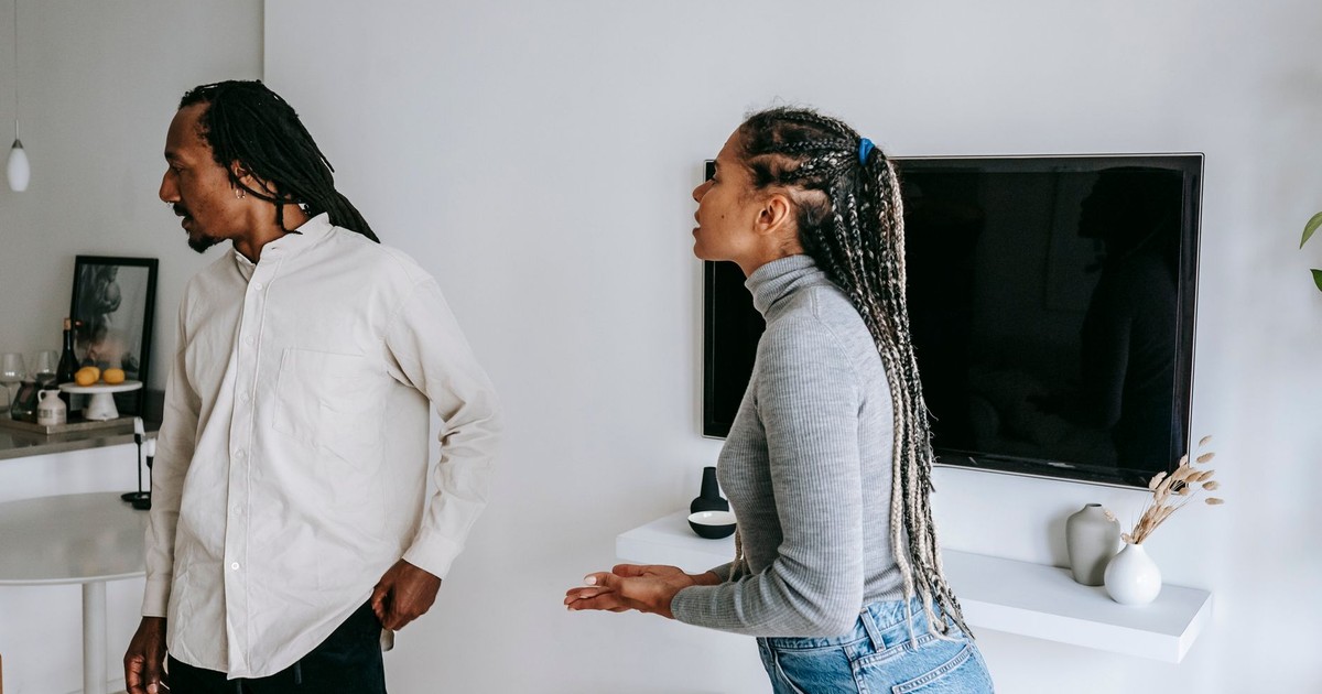 Emotional black couple standing in cozy apartment and having conflict while spending time together