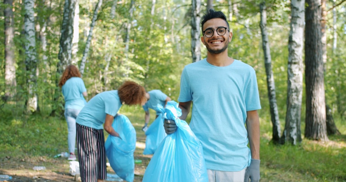 Volunteers cleaning up a forest with blue trash bags.