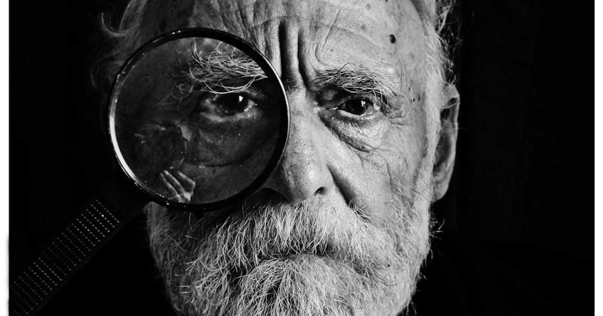grayscale photo of man using magnifying glass