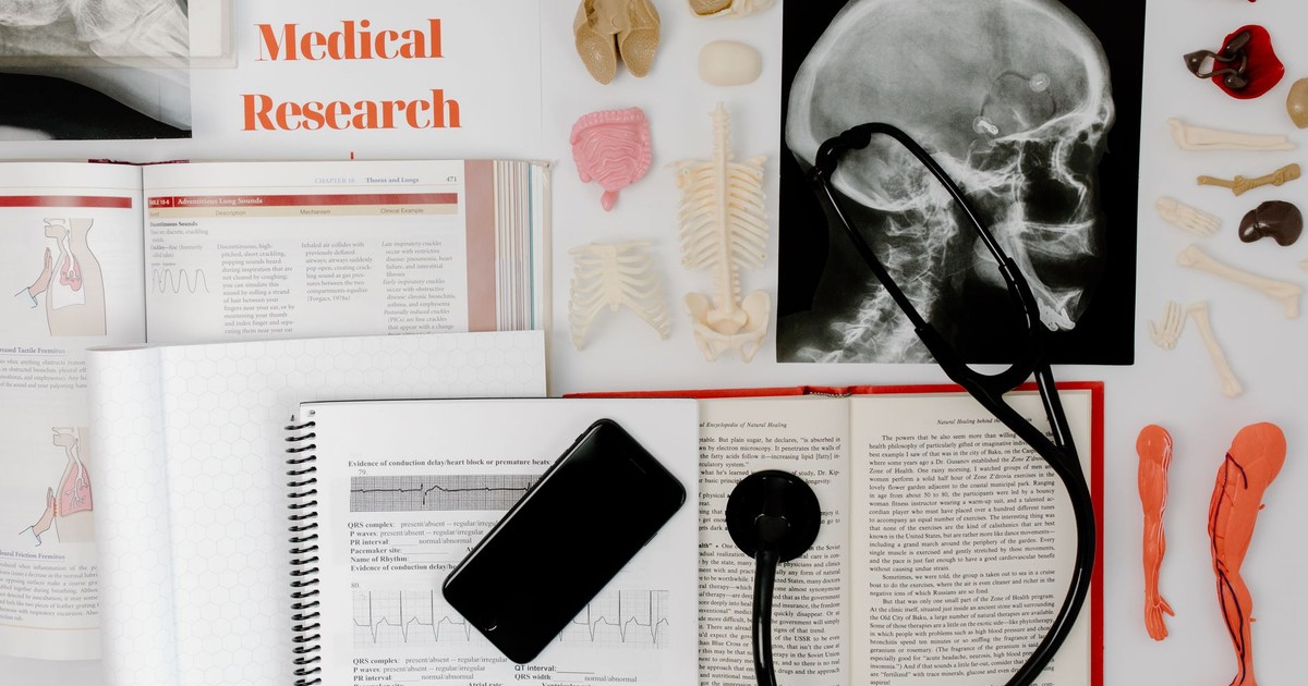 Flat lay of medical research materials with a stethoscope and anatomical models.