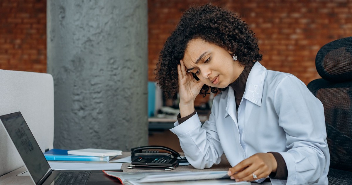 Businesswoman experiencing fatigue while working on financial paperwork at her desk.