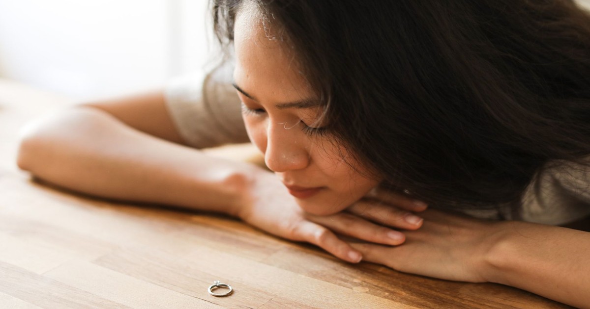 Woman gazing at a wedding ring, contemplating relationship decisions.