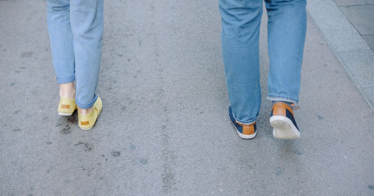 Two people walking casually on a city pavement in jeans and sneakers.