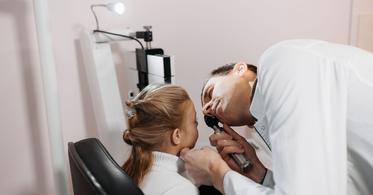 A doctor examines a young girl's ear during a medical appointment in a clinic.