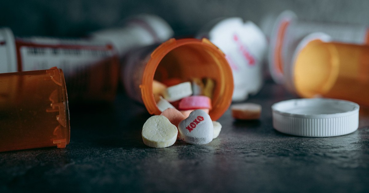 Close-up of open medicine bottles with colorful pills scattered on a dark surface.