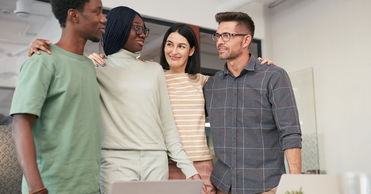 Four diverse colleagues sharing a moment of teamwork and collaboration in an office setting.