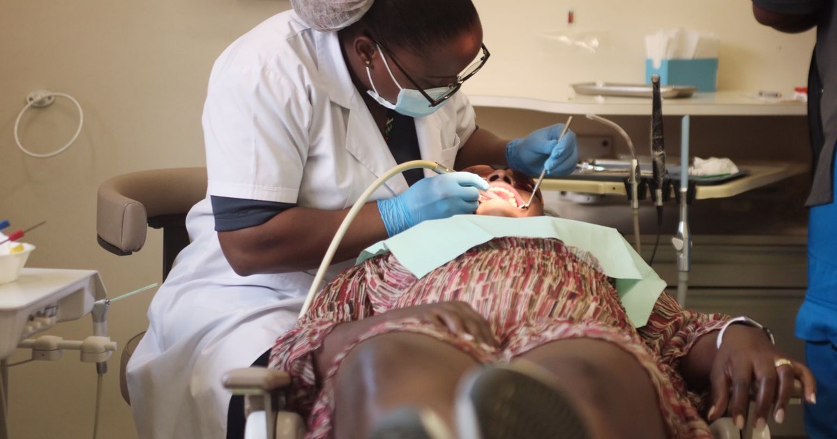A dentist wearing protective gear performs a procedure on a patient in a Zimbabwe clinic.