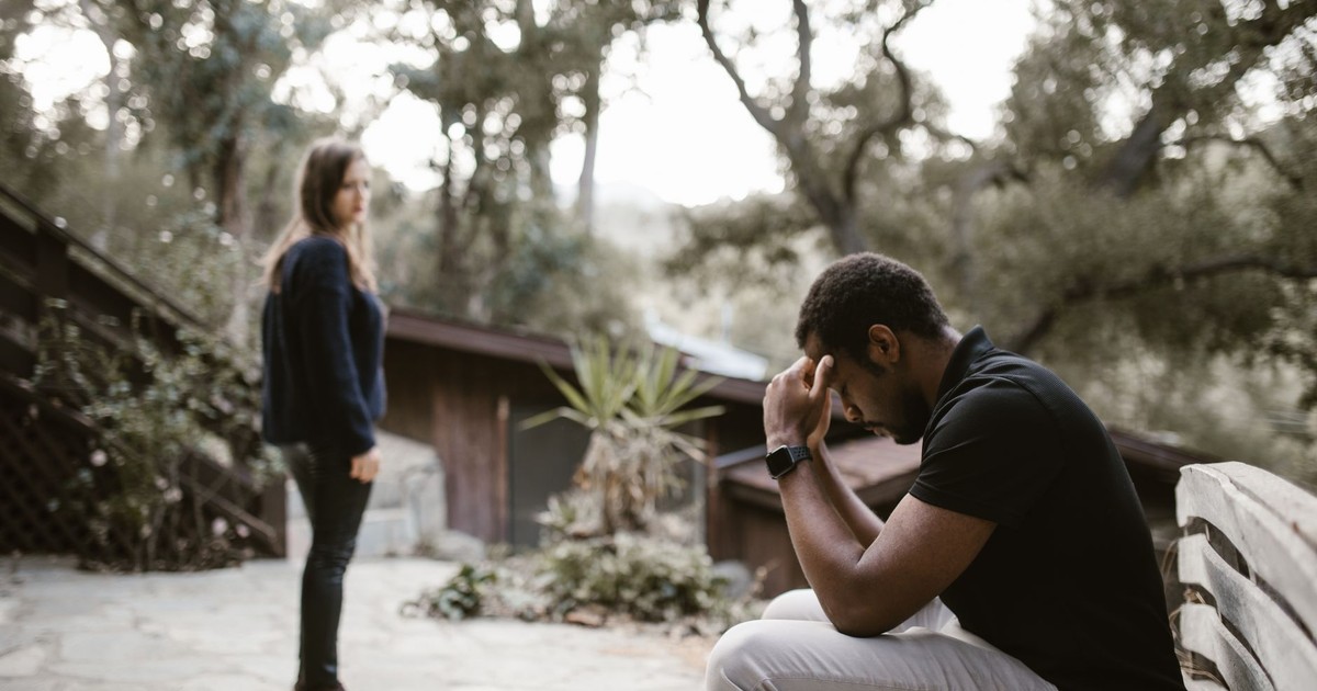 A couple in a tense moment, outdoors on a bench, focusing on emotional distress.
