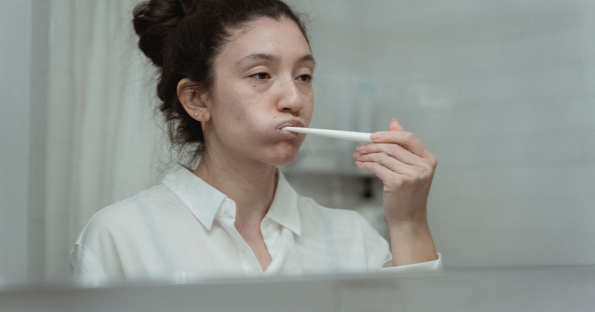 Side view of a woman brushing her teeth, focusing on dental care and hygiene.