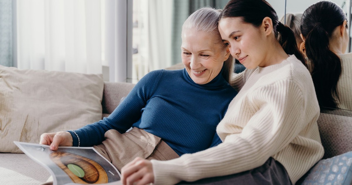 A mother and daughter sharing a joyful moment together on a comfortable couch indoors.
