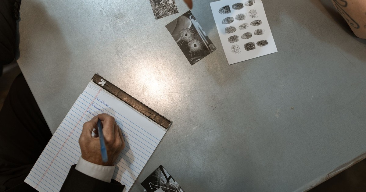 Officers at work reviewing evidence and taking notes in an investigation setting.