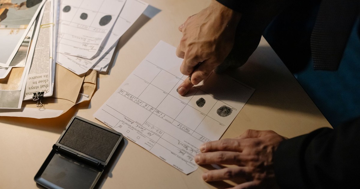 Detailed view of fingerprint analysis on a desk with ink pad and documents, ideal for forensic themes.