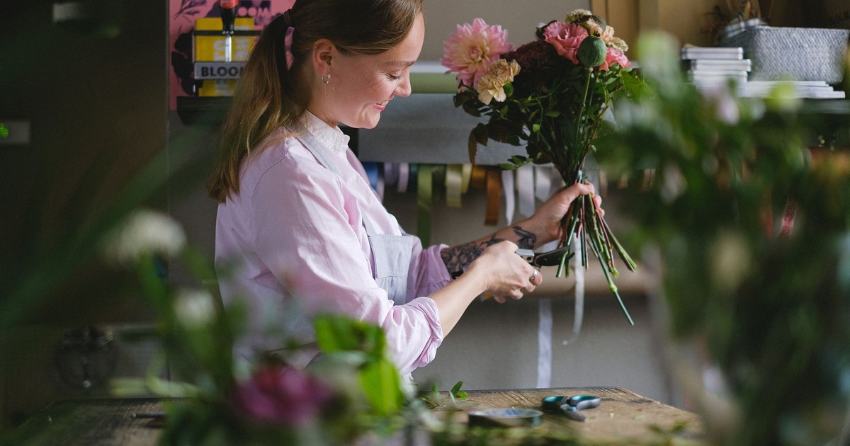 A woman florist arranging a colorful bouquet with precision in a stylish indoor studio.